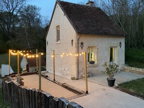 Ein Steinhaus mit geneigtem Dach und einer kleinen Veranda, mit einer Lichterkette geschmückt.