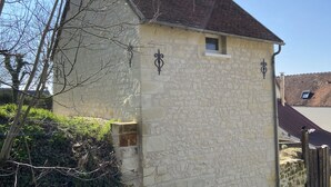 Un edificio de piedra con techo de tejas, una ventana pequeña y una puerta.