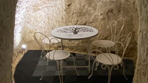 Interior de paredes de piedra con una mesa redonda y cuatro sillas, cada una con un diseño de árbol en el tablero.