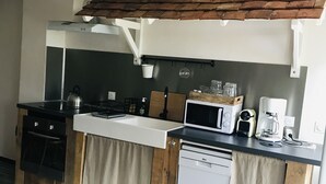 Una cocina compacta con horno integrado, microondas, cafetera y lavabo.