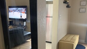 Un salon avec un téléviseur, un canapé, un banc et une plante.