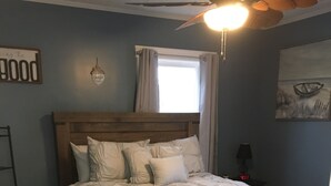 A bedroom with a wooden bed, a nightstand, a wall clock, and a window with curtains. - A Piece of Paradise in the Northeast Kingdom (Troy)