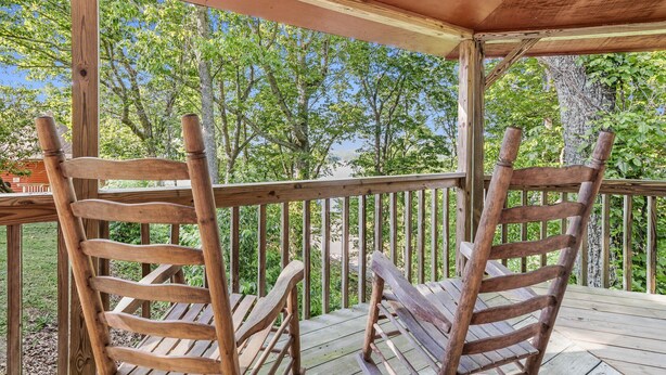 A wooden deck with a covered area, wooden chairs, and a view of trees and a body of water. - Carters Lake Lakeview Cabin #6 includes free boat slip at the Marina (Ellijay)