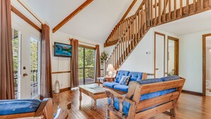 A spacious living room with a wooden staircase, a blue sofa, and a wooden coffee table. - Carters Lake Lakeview Cabin #6 includes free boat slip at the Marina (Ellijay)