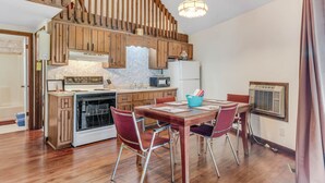 A kitchen with wooden cabinets, a stove, a microwave, and a dining table with chairs. - Carters Lake Lakeview Cabin #6 includes free boat slip at the Marina (Ellijay)