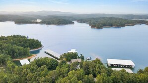 An aerial view of a lakeside property with multiple buildings, docks, and a boat. - Carters Lake Lakeview Cabin #6 includes free boat slip at the Marina (Ellijay)