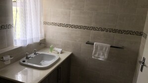 Ein Badezimmer mit Waschbecken, Spiegel und Handtuchhalter.