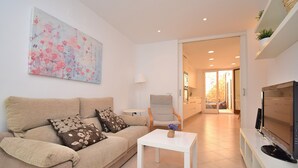 A modern living room with a beige sofa, a white coffee table, and a flat-screen TV.