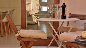 A dining area with a table set for two, a bottle of wine, and two wine glasses.