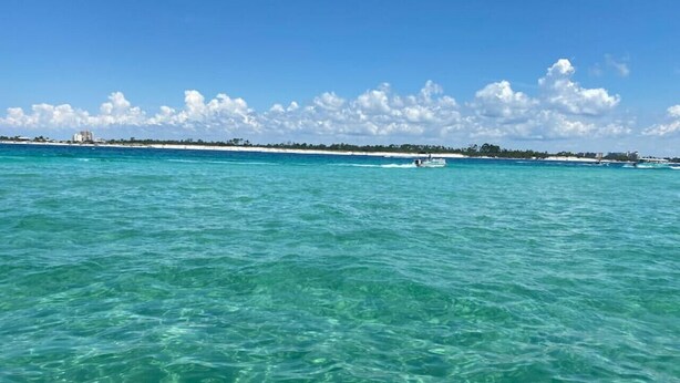 Clear turquoise water with a distant shoreline and buildings.