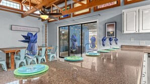 A modern kitchen with granite countertops, a dining area with light blue chairs, and a ceiling fan.