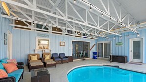 An indoor pool area with wicker furniture and a blue pool.