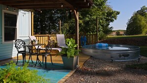 An outdoor deck with a pool, a covered seating area, and a potted plant. - Couples Romantic Country Bungalow, Private, Stock Tank Pool, Birds, Wildlife (Vandalia)