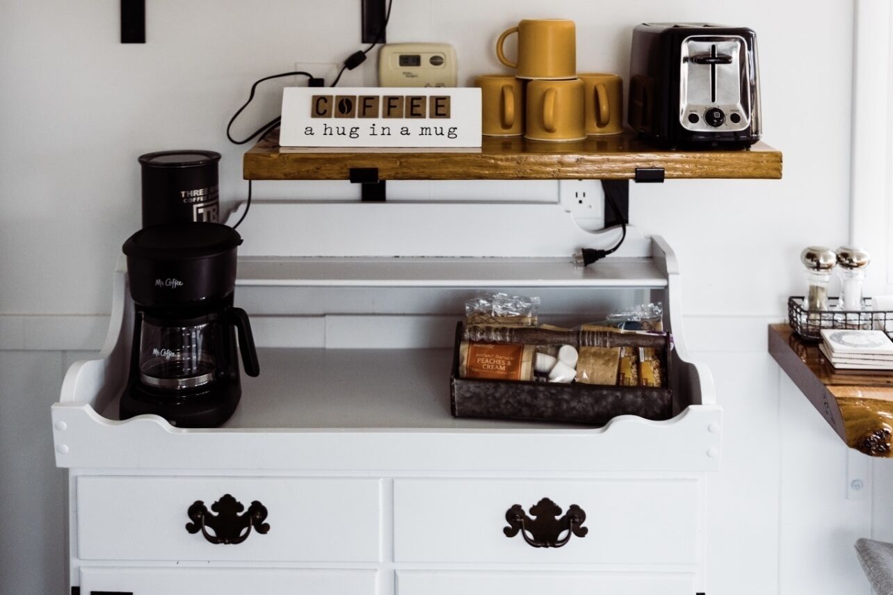 A kitchen counter with a coffee maker, a toaster, and a mug rack.
