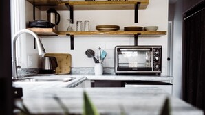 A modern kitchen with a built-in toaster oven, a coffee maker, and a wooden cutting board.