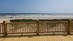 Una terraza de madera con vista a la playa y al océano.