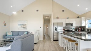 Una cocina moderna con armarios blancos, electrodomésticos de acero inoxidable y una barra con taburetes.