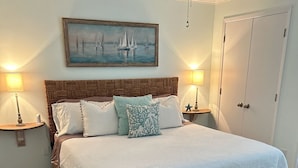 A neatly arranged bedroom with a large bed, two bedside lamps, a wooden headboard, a bench, and a painting of sailboats on the wall. - Orange Beach Oasis  (Orange Beach)