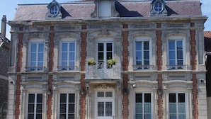 A historic building with a symmetrical facade, large windows, and decorative ironwork on the balconies.