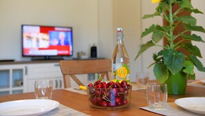 Une table à manger avec une bouteille, un bol de cerises et un tournesol.