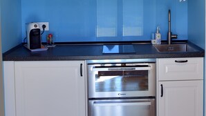 A compact kitchen with white cabinets, a stainless steel oven, a coffee maker, and a sink. - Montefiore House 13 - Iris Farmhouse in the Marche countryside (Marche)