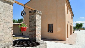 A building with a brick column and a hanging planter with flowers. - Montefiore House 13 - Iris Farmhouse in the Marche countryside (Marche)