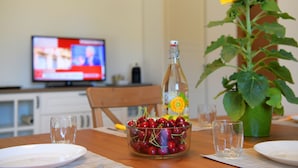 Ein Esstisch mit einer Flasche, einer Schale Kirschen und einer Sonnenblume.