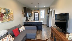 A modern living room with a gray sectional sofa, a brown and white cowhide rug, a wooden entertainment center, and a ceiling fan. - Newer Build-Just a Block to Main St.-Mountain Views (Buena Vista)