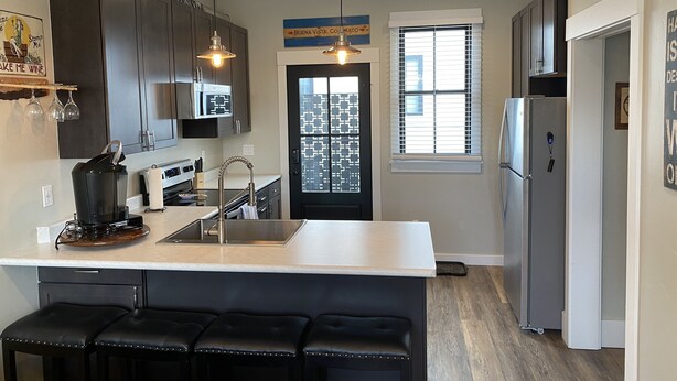 A modern kitchen with dark cabinets, a white countertop, and a central island with bar stools. - Newer Build-Just a Block to Main St.-Mountain Views (Buena Vista)