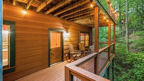 A wooden cabin with a balcony overlooking a forest. - Wooded Smokies Hideaway • Arcade, Pool Table & Hot Tub (Sevierville)