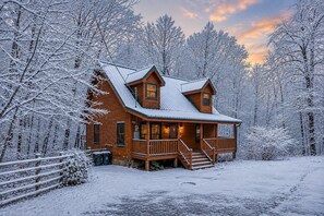 Eine Holzhütte mit Veranda, umgeben von schneebedeckten Bäumen.