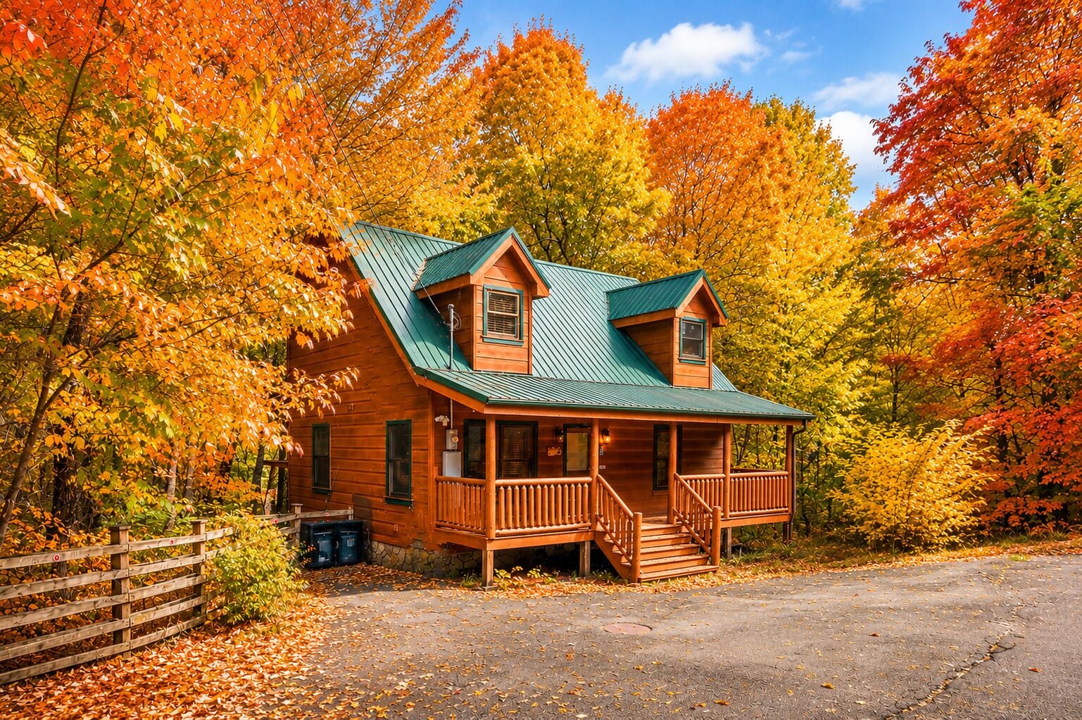 A wooden cabin with a porch, surrounded by autumn foliage.