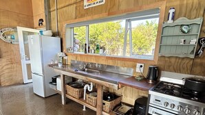 Une cuisine avec un plan de travail en bois, une cuisinière, un réfrigérateur et une fenêtre donnant sur les arbres.
