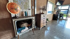 Une pièce comprenant un globe sur un socle, une commode avec des tiroirs, un ventilateur et une carte accrochée au mur.