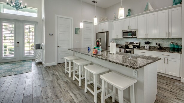 A modern kitchen with white cabinets, a granite countertop, and bar stools.
