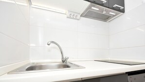 Et moderne køkken med stålvask, hvid bagplade og sorte skabe.