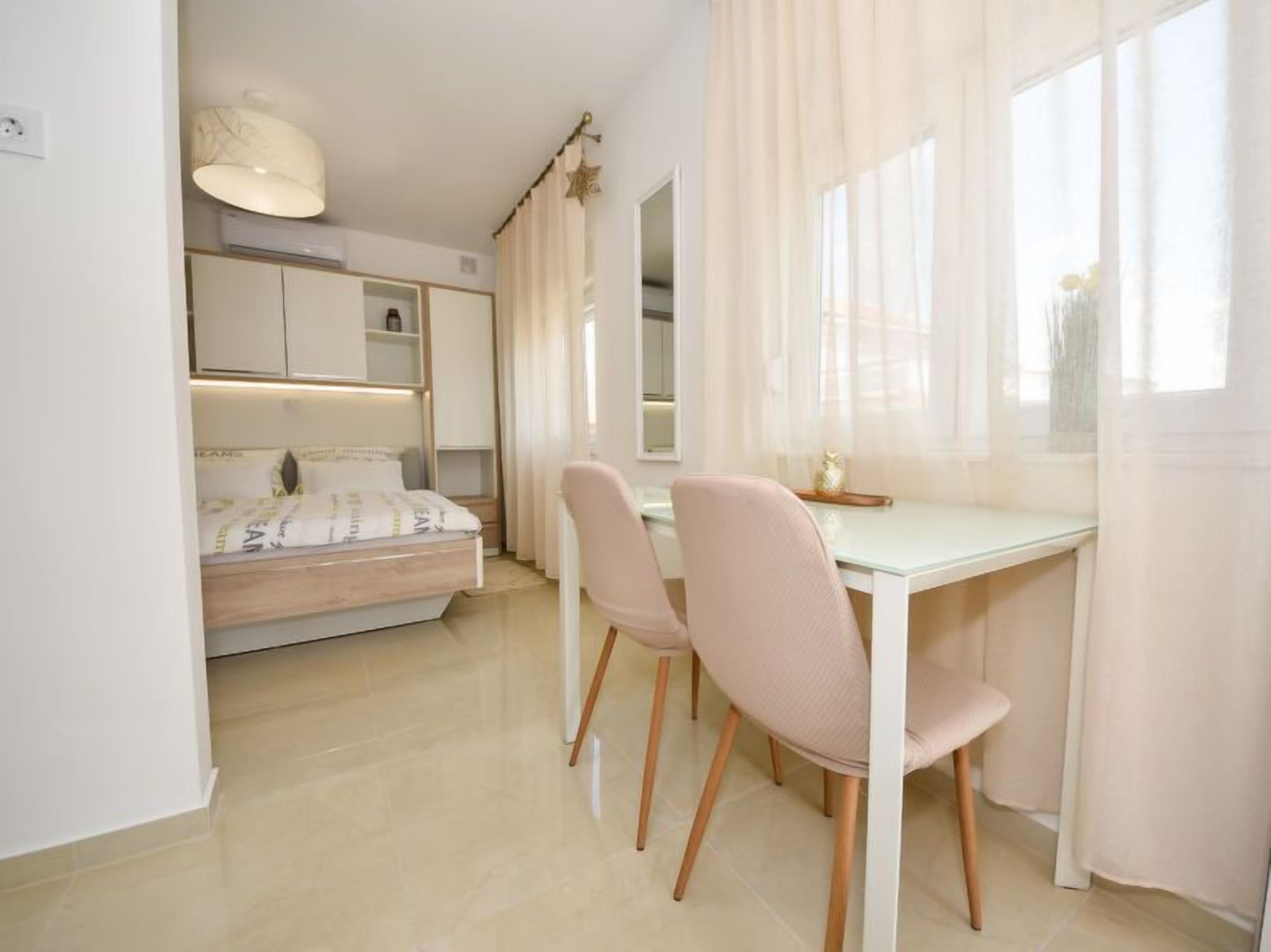 A bedroom with a bed, bedside table, and a desk with chairs.
