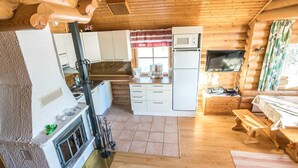 Un intérieur de chalet en bois compact, comprenant une cuisine, un coin repas et une cheminée.