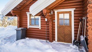 Une cabane en rondins avec une porte et des fenêtres en bois, entourée de neige.