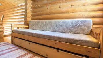 A log cabin interior with a sofa, wooden walls, and a striped rug.