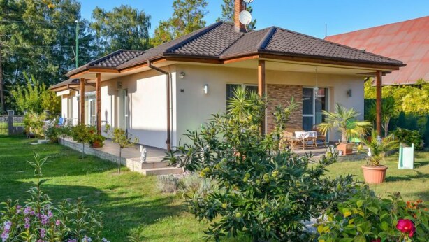 A two-story house with a covered patio, surrounded by a well-maintained garden with various plants and flowers. - Twin Combo by Interhome (Balatonboglar)