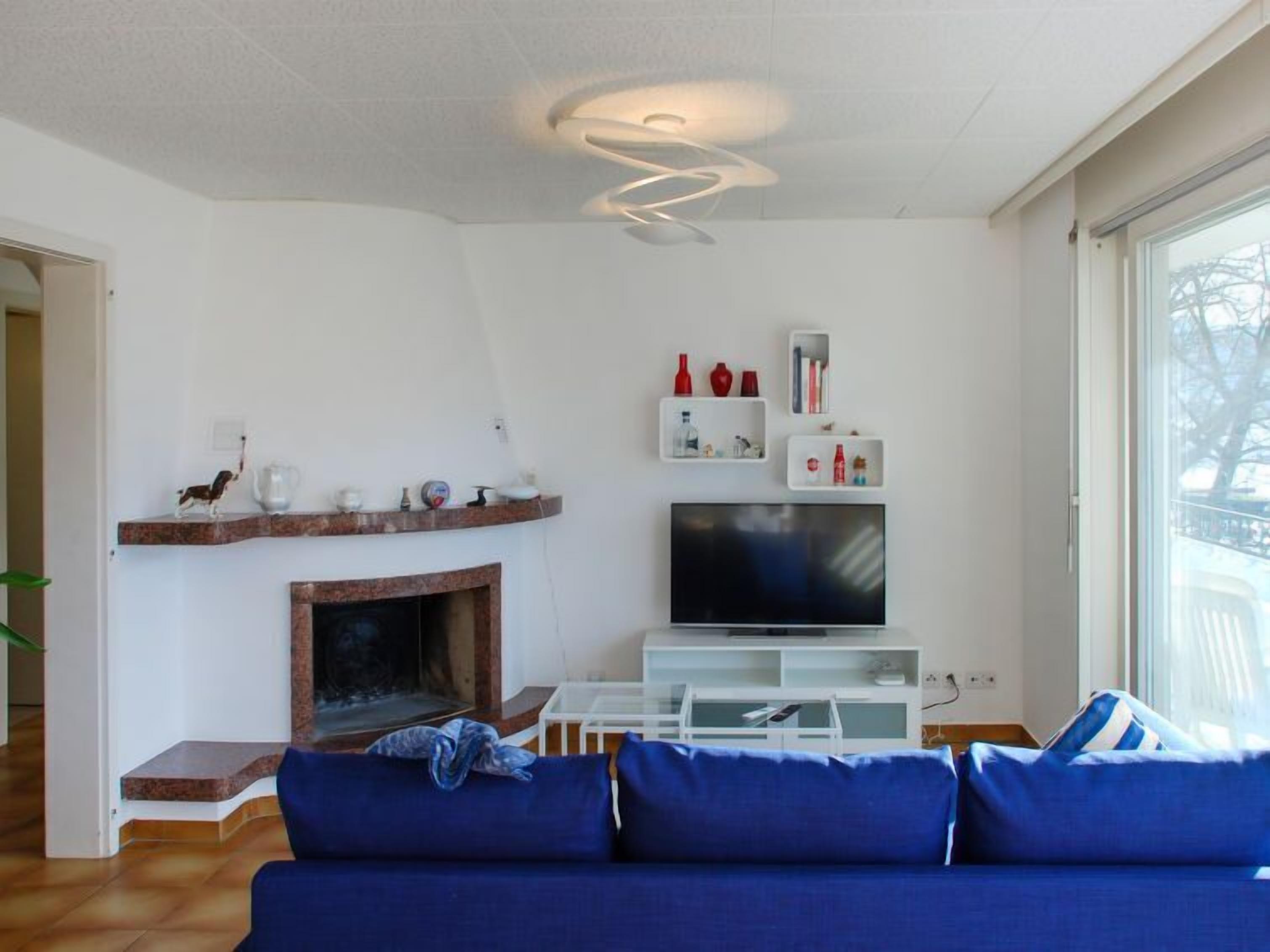 Una sala de estar moderna con chimenea, un televisor de pantalla plana y un sofá azul.