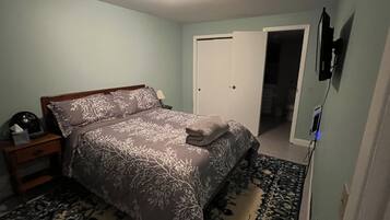 Une chambre à coucher comprenant un lit, une table de chevet et une porte donnant sur une autre pièce.
