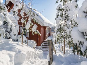 Une cabane en bois entourée d’arbres couverts de neige.