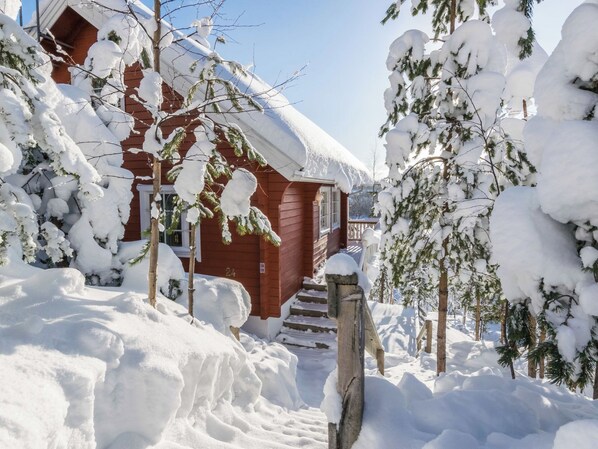 A wooden cabin surrounded by snow-covered trees.