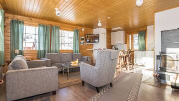 Un intérieur de chalet chaleureux avec un plafond en bois, une cheminée, un téléviseur et un coin repas.