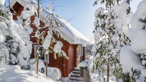 Une cabane en bois entourée d’arbres couverts de neige.