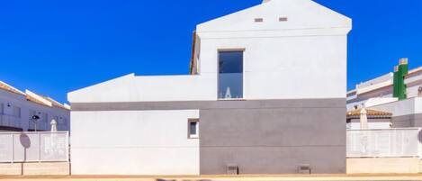 A modern white building with a pool in front.