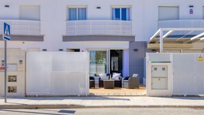 Un hôtel à plusieurs étages doté de balcons, d’un espace extérieur couvert aménagé en salon et d’une entrée sécurisée par un portail.