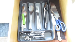 Uma gaveta com diversos utensílios de cozinha, incluindo faca, garfo, colher e espátula.